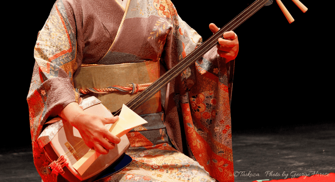 Женщина играет на сямисэне в традиционном костюме